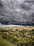 Intense looking clouds over a rural moorland. There is a poorly constructed fence running through the image.