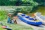 Active boy resting after adventurous experience kayaking on the river on a sunny day during summer vacation