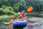 Active happy family. Girl with her brother and mother having fun together enjoying adventurous experience kayaking on the river on a sunny day during summer vacation