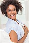 A beautiful mixed race African American girl or young woman laughing with perfect teeth and listening to music on mp3 player and headphones