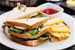 Sandwich with fried eggs, bacon and lettuce served with french fries and ketchup