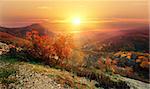 Bright sun over mountains in red autumn