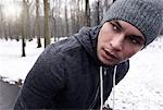 Young man exercising in snowy forest, looking away