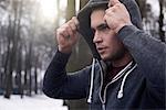 Young man wearing hooded sweatshirt, in snowy, rural landscape