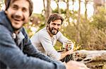 Two men drinking coffee whilst sitting in forest, Deer Park, Cape Town, South Africa