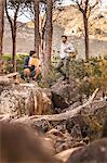 Male hikers looking at map on forest rock formation, Deer Park, Cape Town, South Africa