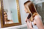 Woman looking in mirror  brushing hair