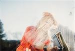 Woman outdoors cleaning soapy window with squeegee