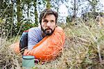 Man watching from sleeping bag in forest, Deer Park, Cape Town, South Africa