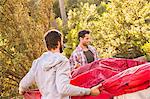 Two men putting up dome tent in forest, Deer Park, Cape Town, South Africa