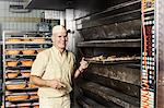 Happy baker placing tray of sliced bread into oven