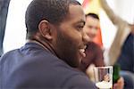 Over the shoulder view of man holding glass of beer looking away smiling