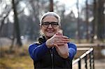 Woman wearing glasses arm out stretching hand, looking at camera smiling