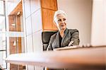 Businesswoman sitting at desk arms crossed looking away