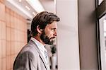 Side view of bearded businessman looking out of window