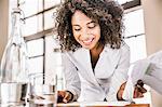 Curly haired business woman looking down at paperwork smiling