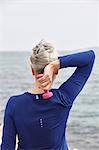 Mature woman beside sea, exercising with hand weights, rear view