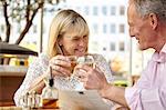 Mature dating couple raising a glass of white wine at restaurant table