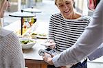 Woman using smartphone contactless payment at restaurant table, London, UK