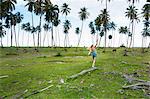 Young woman balancing on fallen tree trunk amongst palms, Dominican Republic, The Caribbean