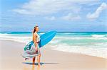 Young woman carrying surfboard on beach, Dominican Republic, The Caribbean