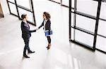 High angle view of businesswoman and man shaking hands at  office entrance