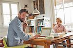 Father on phone while working in home office with son