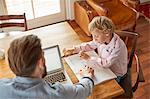 Father helping son with homework in home office