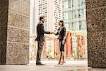 Businessman and woman shaking hands outside office, Dubai, United Arab Emirates