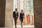 Businessman and woman walking and talking outside office, Dubai, United Arab Emirates