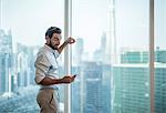 Businessman reading smartphone text at window with view of Burj Khalifa, Dubai, United Arab Emirates