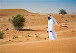 Middle eastern man wearing traditional clothes walking in desert, Dubai, United Arab Emirates