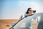 Female tourist photographing from off road vehicle in desert, Dubai, United Arab Emirates