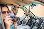 Female tourist in off road vehicle in desert taking photographs, Dubai, United Arab Emirates
