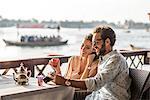 Romantic couple reviewing camera at Dubai marina cafe, United Arab Emirates