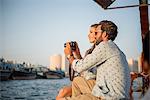 Romantic couple reviewing camera on boat at Dubai marina, United Arab Emirates