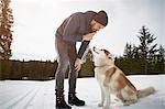 Young man training husky in snow covered landscape, Elmau, Bavaria, Germany