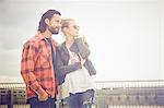 Cool mid adult couple looking out from rooftop parking lot