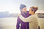 Mid adult woman hugging boyfriend on rooftop parking lot