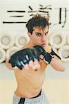 Man wearing kickboxing gloves in sparring stance looking at camera