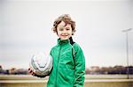 Boy holding football looking at camera smiling