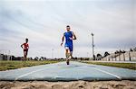 Young male long jumper sprint training at sport facility