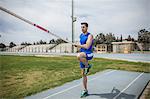 Young male pole vaulter pole vaulting at sport facility