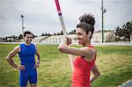 Instructor advising young female pole vaulter at sport facility