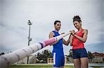 Man instructing young female pole vaulter at sport facility