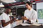 Employee in restaurant talking with chef, making notes in notebook