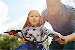 Father teaching daughter to ride bicycle