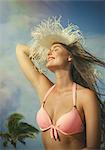 Beautiful young woman holding onto sun hat at Miami beach, Florida, USA