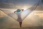 Rear view of young woman lying on hammock at sunset, Miami beach, Florida, USA