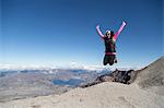 Young woman at mountain top, jumping for joy, Mt. St. Helens, Oregon, USA